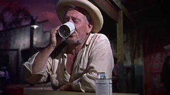 Movie still from “The Old Man and the Sea” (1958), directed by Fred Zinnemann – An old man sitting at a table drinking a cup of coffee; Medium shot, Low angle