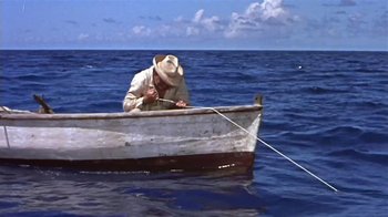 Movie still from “The Old Man and the Sea” (1958), directed by Fred Zinnemann – A man in a hat is in a boat in the ocean; Wide shot, High angle