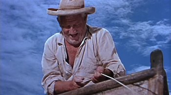 Movie still from “The Old Man and the Sea” (1958), directed by Fred Zinnemann – An old man wearing a cowboy hat is tying a string; Medium shot, Low angle