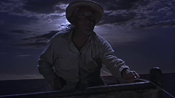 Movie still from “The Old Man and the Sea” (1958), directed by Fred Zinnemann – A man wearing a cowboy hat standing in front of a dark sky; Medium shot, Low angle