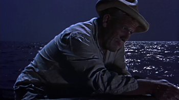 Movie still from “The Old Man and the Sea” (1958), directed by Fred Zinnemann – A man wearing a cowboy hat is laying on a boat; Medium shot, High angle