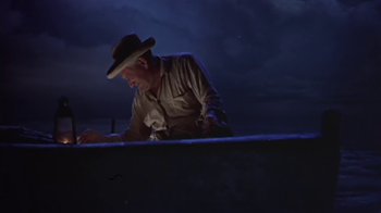 Movie still from “The Old Man and the Sea” (1958), directed by Fred Zinnemann – A man wearing a hat is looking down at something on the ground; Medium shot, High angle