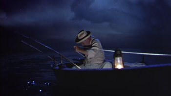 Movie still from “The Old Man and the Sea” (1958), directed by Fred Zinnemann – An older man sitting on a boat at night; Wide shot, High angle