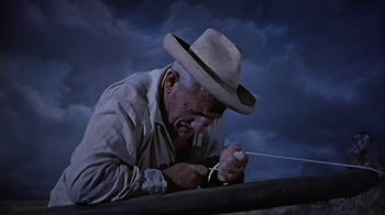 Movie still from “The Old Man and the Sea” (1958), directed by Fred Zinnemann – An old man wearing a cowboy hat is tying a string; Medium shot, Low angle