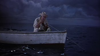Movie still from “The Old Man and the Sea” (1958), directed by Fred Zinnemann – An older man sitting in a boat on the water; Wide shot, High angle
