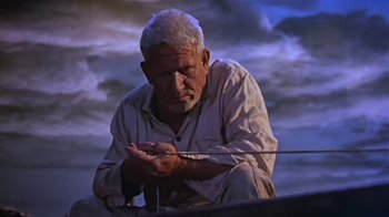 Movie still from “The Old Man and the Sea” (1958), directed by Fred Zinnemann – An old man sitting on top of a boat in the water; Medium shot, High angle