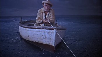 Movie still from “The Old Man and the Sea” (1958), directed by Fred Zinnemann – An old man sitting in a boat on the beach; Wide shot, High angle