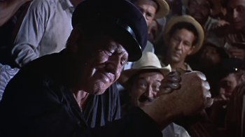 Movie still from “The Old Man and the Sea” (1958), directed by Fred Zinnemann – An old man in a crowd of people with hats on; Close Up shot, Low angle