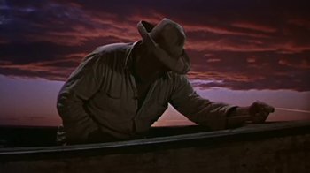 Movie still from “The Old Man and the Sea” (1958), directed by Fred Zinnemann – A man wearing a hat is leaning on a boat; Medium shot, Low angle