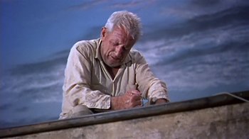 Movie still from “The Old Man and the Sea” (1958), directed by Fred Zinnemann – An older man writing with a pen on a ledge; Medium shot, Low angle