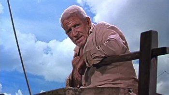 Movie still from “The Old Man and the Sea” (1958), directed by Fred Zinnemann – An older man holding a hammer on top of a building; Medium shot, Low angle