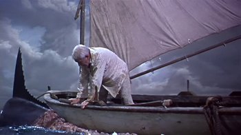 Movie still from “The Old Man and the Sea” (1958), directed by Fred Zinnemann – An older man in white shirt on a boat; Wide shot, Low angle