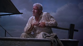 Movie still from “The Old Man and the Sea” (1958), directed by Fred Zinnemann – An older man sitting on a boat in the water; Medium shot, Low angle