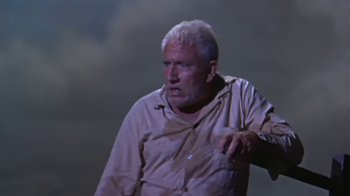 Movie still from “The Old Man and the Sea” (1958), directed by Fred Zinnemann – An older man with a white beard and a red forehead; Medium shot, Low angle
