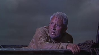 Movie still from “The Old Man and the Sea” (1958), directed by Fred Zinnemann – An older man is sitting on a ledge; Medium shot, Low angle