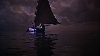 Movie still from “The Old Man and the Sea” (1958), directed by Fred Zinnemann – A person in a sail boat on a body of water at night; Wide shot, High angle