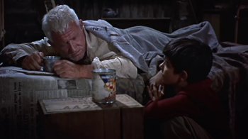Movie still from “The Old Man and the Sea” (1958), directed by Fred Zinnemann – An older man laying on the ground next to a young boy; Medium shot, Low angle