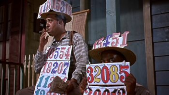 Movie still from “The Old Man and the Sea” (1958), directed by Fred Zinnemann – Two men with numbers on their hats are smoking a cigarette; Medium shot, Low angle
