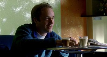 Movie still from “The One and Only” (1999), directed by Susanne Bier – A man sitting at a table with a cup of coffee in front of him; Close Up shot, Over the shoulder angle