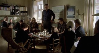 Movie still from “The One and Only” (1999), directed by Susanne Bier – A group of people sitting around a table with food on top of it; Wide shot, Over the shoulder angle