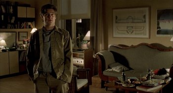 Movie still from “The One and Only” (1999), directed by Susanne Bier – A man standing in front of a couch in a living room; Medium shot, Low angle