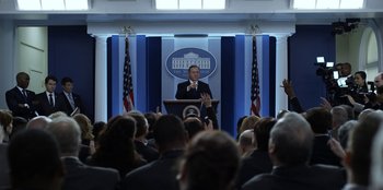 Movie still from “House of Cards” (2013), created by Beau Willimon – A man is speaking at a podium in front of an audience; Medium shot, Over the shoulder angle