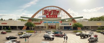 Movie still from “The One and Only Ivan” (2020), directed by Thea Sharrock – A big top mall with cars parked in front of it; Extreme Wide shot, Low angle