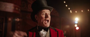 Movie still from “The One and Only Ivan” (2020), directed by Thea Sharrock – An older man wearing a red jacket and a black top hat; Close Up shot, Low angle