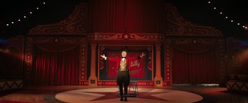 Movie still from “The One and Only Ivan” (2020), directed by Thea Sharrock – A man standing on a stage in front of a red curtain; Wide shot, Low angle