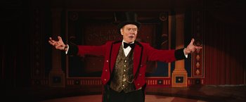 Movie still from “The One and Only Ivan” (2020), directed by Thea Sharrock – A man in a top hat and a red jacket standing in front of a stage; Medium shot, Low angle