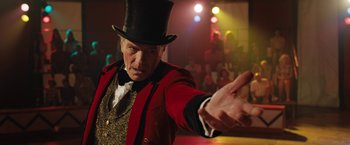 Movie still from “The One and Only Ivan” (2020), directed by Thea Sharrock – A man wearing a top hat and a red jacket; Close Up shot, Low angle