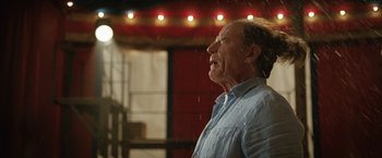 Movie still from “The One and Only Ivan” (2020), directed by Thea Sharrock – An older man standing in the pouring rain with his mouth open; Close Up shot, Low angle