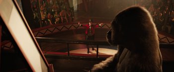 Movie still from “The One and Only Ivan” (2020), directed by Thea Sharrock – A man in a red jacket is on a stage with an animal; Medium shot, Over the shoulder angle