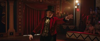 Movie still from “The One and Only Ivan” (2020), directed by Thea Sharrock – A man wearing a red jacket and a black top hat; Medium shot, Low angle