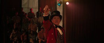 Movie still from “The One and Only Ivan” (2020), directed by Thea Sharrock – A man wearing a red jacket and a black top hat; Medium shot, Low angle
