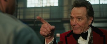 Movie still from “The One and Only Ivan” (2020), directed by Thea Sharrock – A man in a red jacket pointing to the side; Close Up shot, Low angle
