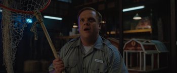 Movie still from “The One and Only Ivan” (2020), directed by Thea Sharrock – A man holding a wooden stick in a room; Medium shot, Low angle