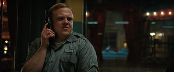 Movie still from “The One and Only Ivan” (2020), directed by Thea Sharrock – A man in a gray shirt is talking on a phone; Close Up shot, Low angle