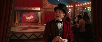 Movie still from “The One and Only Ivan” (2020), directed by Thea Sharrock – A man in a top hat and a red jacket standing in front of a circus tent; Medium shot, Over the shoulder angle