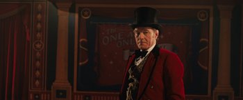 Movie still from “The One and Only Ivan” (2020), directed by Thea Sharrock – An older man wearing a red jacket and a black top hat; Medium shot, Low angle