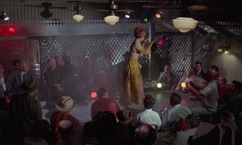 Movie still from “The Oscar” (1966), directed by Russell Rouse – A woman in a yellow dress is on a stage; Wide shot, Low angle