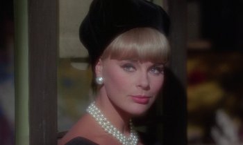 Movie still from “The Oscar” (1966), directed by Russell Rouse – A woman wearing a black hat and pearls; Close Up shot, Over the shoulder angle
