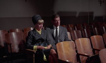 Movie still from “The Oscar” (1966), directed by Russell Rouse – A man and a woman sitting in a row of chairs; Wide shot, High angle