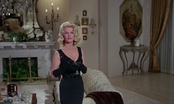 Movie still from “The Oscar” (1966), directed by Russell Rouse – A woman in a black dress in a living room; Medium shot, Low angle