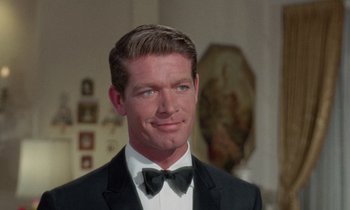 Movie still from “The Oscar” (1966), directed by Russell Rouse – A person wearing a suit and bow tie; Close Up shot, Over the shoulder angle