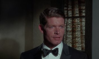 Movie still from “The Oscar” (1966), directed by Russell Rouse – A person wearing a suit and bow tie; Close Up shot, Over the shoulder angle