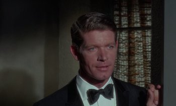 Movie still from “The Oscar” (1966), directed by Russell Rouse – A person wearing a suit and bow tie; Close Up shot, Over the shoulder angle