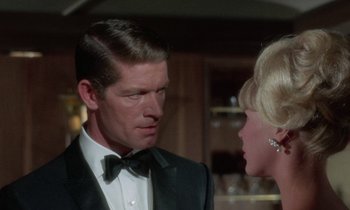 Movie still from “The Oscar” (1966), directed by Russell Rouse – A man in a tuxedo and a woman in a black suit; Close Up shot, Over the shoulder angle