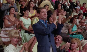 Movie still from “The Oscar” (1966), directed by Russell Rouse – A man in a crowd clapping his hands in front of a crowd of onlookers; Medium shot, Low angle