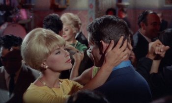 Movie still from “The Oscar” (1966), directed by Russell Rouse – An older woman and a younger man are dancing together; Close Up shot, Over the shoulder angle